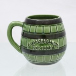 Caneca de coleção em faiança vidrada das Caldas da Rainha, de tradição humorístico-satírica portuguesa("malandrice das Caldas"), circa meados do século XX. Modelada em forma de barril com gomos em relevo verticais e faixas horizontais escuras, ladeada por alça integrada em formato de arco. A porção frontal ostenta faixa em relevo com a inscrição identificadora "Caldas da Rainha / Portugal"; interior abriga um elemento fálico oculto modelado com cobertura esmaltada em tom vermelho na extremidade superior. Medidas: Alt.: 9,5 x Comp.: 12 x Larg.: 10cm.