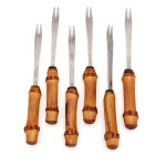 Conjunto de seis garfos para aperitivos, manufatura Eberle, confeccionadas em aço inoxidável, com hastes alongadas terminadas em dois dentes e cabos em madeira simulando bambu natural, aproveitando os nós do colmo como elementos de acabamento. Hastes marcadas "EBERLE INOX". Utensílios destinados ao serviço individual de petiscos, azeitonas, queijos, frios e pequenos aperitivos. Medidas: Comp.:  14,5 cm.