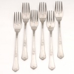 HERCULES INOX. Modelo Classique. Conjunto composto por seis(06) garfos para sobremesa confeccionados em aço inoxidável, datável do período circa 1960-1970. Executados ao estilo francês do período Luís XV, apresentam cabos de perfil sinuoso e terminação espatulada, enriquecidos por ornamentação seriada em relevo que conjuga motivos de volutas, rocalhas e filetes perimetrais. O reverso das hastes exibe a marca em baixo-relevo "HERCULES INOX". Medidas: Comp.: 16,5 cm.