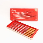 Conjunto de seis garfos para fondue, manufatura Cris Inox, fabricação nacional. Hastes alongadas em aço inoxidável, terminadas em duas pontas, com cabos torneados em madeira e marcadores coloridos nas extremidades, destinados à identificação individual. Conserva embalagem original com a inscrição "Garfos para Fondue - Cris Inox". Medidas caixa: Alt.: 2 x Comp.: 30 x Larg.: 13cm; Medidas garfo: Comp.:  28 cm.