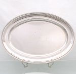 WOLFF. Elegante travessa confeccionada em metal espessurado à prata, formato oval de centro ligeiramente rebaixado, borda de contorno relevado. Marca da manufatura no verso. Medidas: Comp.: x Larg.: