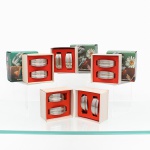 Conjunto de dez(10) porta-guardanapos confeccionados em aço inoxidável, formato arqueado, constituídos por lâmina metálica curvada com extremidades planas para apoio. Acondicionados em cinco embalagens originais, cada uma contendo um par, com indicação impressa "Porta Guardanapos (1 par)". Medidas: Alt.: 3,5 x Comp.: 6 x Larg.: 2,5 cm.