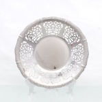 Cesto para pães confeccionado em metal prateado. formato hemisférico de perfil baixo, com fundo liso e parede vazada, composta por painéis alternados de motivos vegetalistas estilizados. Bordo recortado, ornamentado em relevo por sequência de volutas. Apresenta sinais de uso. Medidas: Alt.: 5 x Diam.: 28,5 cm.