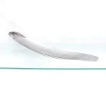 Centro de mesa / bandeja escultórica em alumínio, manufatura Don Sheil, Austrália. Formato alongado e perfil arqueado, executada em liga de alumínio de alta pureza, com superfície martelada e bordas elevadas. Uma das extremidades recebe aplicação escultórica de folhas e fruto de eucalipto(gumnut), motivo associado à produção de Don Sheil e à flora australiana. Conserva etiqueta no reverso com assinatura fac-similar "Don Sheil  Made in Australia". Medidas: Alt.: 8,5 x Comp.: 62,5 x Larg.: 11 cm.