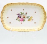 Porcelana Real, Mauá - SP(Fundada em 1943 por Fritz Erwin Schmidt). Travessa em porcelana nacional, formato retangular com cantos arredondados e bordo recortado, apresenta decoração policromada com ramalhete floral central, pequenos motivos florais dourados e faixa periférica em amarelo, delimitada por friso e arabescos a ouro. Verso com marca de manufatura "Real - S. Paulo  Made in Brazil". Medidas: Alt.: 2,5 x Comp.: 18,5 x Larg.: 12 cm.