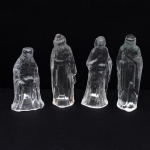 Conjunto de quatro(04) figuras de presépio em vidro moldado. Composto por quatro personagens da Natividade trajando vestes longas, executados em vidro incolor transparente moldado, com modelagem figurativa em relevo. Medidas maior: Alt.: 10 x Comp.: 3,5 x Larg.: 3 cm. Medidas menor: Alt.: 8 x Comp.: 4,5 x Larg.: 3,5 cm.