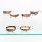 Conjunto de taças para sobremesa confeccionado em metal prateado, bojo hemisférico assente sobre três pés esféricos, alça lateral em voluta. Composto de seis(06) unidades. Necessitam polimento e/ou refazer banho de prata. Medidas: Alt.: 4,5 x Comp.: 11 x Larg.: 9 cm.