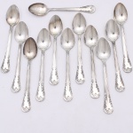 MERIDIONAL EPNS 100. Elegante conjunto de colheres médias confeccionadas em metal espessurado à prata(EPNS 100), cabo violinado com filetes longitudinais em baixo-relevo e terminação ornamentada por composição de concheados, volutas, flores e folhagens em relevo. Marca da manufatura puncionada no verso. Composto de doze(12) unidades. Medida: Comp.: 11cm.