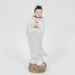 Estátua representando Guanyin executada em porcelana esmaltada, base moldada em forma de nuvens. Apresenta vestes brancas fluídas, adornos dourados e pedra verde no peito, postura serena e mãos juntas, símbolo de oração ou meditação. Produção chinesa, c. 19601980. Usada tradicionalmente como objeto devocional ou decorativo. Guanyin é a deusa da misericórdia e da compaixão no budismo Mahayana, especialmente reverenciada na China, Japão (onde é chamada Kannon), Vietnã e Coreia. Ela é considerada uma bodisatva que ouve os lamentos do mundo e ajuda os necessitados. Estátuas como essa são comuns em altares domésticos ou como objetos decorativos espirituais. Apresenta selo ao fundo. Med.: Alt. 30,5 x Comp. 11 x Larg. 8 cm.