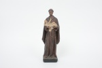 ARTE SACRA. São Benedito com Menino Jesus. Imagem Sacra executada em estuque policromado. A composição apresenta o santo em postura frontal, envergando hábito franciscano em tom marrom, cingido por cordão com rosário pendente. Sustenta nos braços o Menino Jesus reclinado, em gesto de ternura. Policromia em tonalidades terrosas, com vestígios de desgaste e craquelê característicos do tempo. Med.: Alt. 27 x Comp. 9 x Larg. 7 cm.