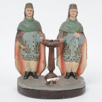 ARTE SACRA. Santos Cosme e Damião. Imagem Sacra executada em estuque policromado. Representação dos santos gêmeos de pé, ladeando mesa alta com instrumentos de ofício médico. Ambos portam penas de martírio nas mãos e vestem túnicas azuladas decoradas por ramos estilizados, capas avermelhadas e mantos verdes, com gorros cilíndricos. A composição segue a iconografia tradicional dos santos anárgiros, originalmente acompanhada por figura central menor  Doum, aqui ausente , restando na base apenas o fragmento da perna pertencente a esse personagem. Apreseta desgastes do tempo, visíveis nas fotos. Med.: Alt. 26 x Comp. 21 x Larg. 12,5 cm.