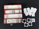 Porta Moedas - 2 caixas vermelhas de papelão grosso para guardar coin holders, 43 coin holders vazios e sem uso e 11 envelopes para moedas vazios. São 32 coin holders de 40 mm, 6 coin holders de 22,5 mm, 2 coin holders de 27,5 mm, 1 coin holder de 36,5 mm, 2 coin holders de 29 mm, 43 envelopes para moedas.