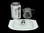 Lote com 3 peças utilitárias, sendo: 1) Grande bule da marca Meridional (10 cm d x 15 cm alt). 2) Porta condimentos em cerâmica com tampa e colher acoplada feitas em inox e detalhe na tampa com visor (11 cm d x 22 cm alt). 3) Travessa em cerâmica com tampo de vidro e pega em inox - 32 cm x 22 cm. (peças usadas).
