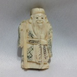 NETSUKE - Antigo netsuke japonês, finamente esculpido à mão em marfim trabalhado, datado do final do século XIX ao início do século XX, representando um ancião de longas barbas e trajes tradicionais, segurando uma folha de palmeira e apoiado em uma bengala. A peça apresenta delicados detalhes incisos e vestimentas ornamentadas, com perfurações no verso, características dos netsukes utilizados como fecho em vestimentas tradicionais japonesas. Apresenta ausência da mão direita, condição considerada na avaliação, além de pátina compatível com a idade. Belo exemplar de arte oriental, de interesse para colecionadores. Aprox. 6 cm. Detalhes conforme fotos, _(ºLº)_ Caso necessite, tire todas suas dúvidas via atendimento personalizado por WhatsApp: (11) 98681-9377. Não deixe para última hora! Antecipadamente agradecemos pelo seu lance. Sem testes ou garantias futuras de originalidade, funcionalidade, material ou procedência.