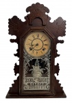 ANSONIA - Relógio de parede Ansonia, modelo americano antigo em madeira entalhada, com mostrador em algarismos romanos, porta envidraçada decorada com gravação floral e mecanismo de corda com pêndulo. Acompanha chave. Peça de caráter decorativo e colecionável, representativa da tradicional manufatura da Ansonia Clock Company, importante fabricante de relógios dos séculos XIX. Funcionando mas sem garantias futuras. Mede 52 x 33 cm.