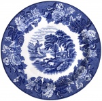 Prato decorativo em faiança inglesa Woods Ware, série English Scenery, decoração em azul cobalto sobre fundo branco, apresentando cena campestre com moinho, árvores e figuras rurais, cercada por rica borda floral em estilo tradicional. Marca da manufatura no verso. Peça de forte apelo decorativo e colecionável. Mede 23cm.