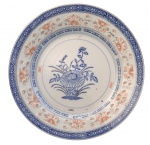 Prato em porcelana chinesa, decoração policromada em tons de azul e ferro vermelho, com motivo floral central e borda ornamentada em padrão geométrico. Marca na base Made in China. Apresenta sinais compatíveis com o uso e o tempo. Medida: 23 cm de diâmetro.