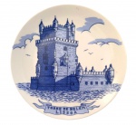 Prato decorativo em porcelana, com decoração em azul sob esmalte representando a Torre de Belém, Lisboa, inscrição frontal Torre de Belém Lisboa e verso com inscrição Recordação de Lisboa. Peça de parede para coleção ou decoração. Medida: 20 cm de diâmetro.