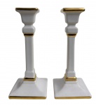 Par de castiçais em porcelana branca europeia com elegante acabamento em dourado, de linhas retas e design clássico. Apresentam leves sinais de uso compatíveis com o tempo. Medem 19 cm de altura.