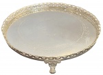 Bandeja circular em metal espessurado a prata, ricamente cinzelada com decoração floral, montada em estrutura metálica com borda vazada e três pés ornamentados. Peça de elegante acabamento, ideal para composição decorativa ou apoio de mesa. Mede 38,5cm de diâmetro.
