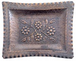 Antiga bandeja retangular em cobre repuxado e martelado, decorada em relevo com composição floral ao centro e bordas onduladas ricamente cinzeladas. Peça artesanal de caráter decorativo, apresentando pátina e sinais naturais do tempo.Medidas: 28  22 cm.