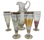 VENEZA - Conjunto para refrescos em cristal veneziano artístico, composto por 1 jarra e 4 copos altos decorados a mão com delicadas faixas douradas. A jarra apresenta acabamento com efeito craquelado e elegante alça aplicada, formando um conjunto de apelo decorativo e colecionável. Pequenos sinais do tempo compatíveis com o uso. Maior medida: 30 cm (jarra).