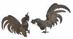 Par de esculturas portuguesas de galos em bronze, ricamente modeladas, representando aves em posição de combate, com caudas plumosas estilizadas e base integrada. Trabalho decorativo de forte apelo ornamental. Medem 28 cm de altura.