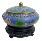 Magnifico potiche com tampa em esmalte cloisonné sobre cobre, decoração policromada com flores, folhagens e pássaros sobre fundo azul, arremates em metal dourado e base em madeira entalhada. China, século XIX. Mede 22 cm.