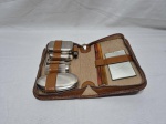 Antigo estojo de higiene e barbear masculino para viagem, em couro legítimo marrom com fechamento em zíper, contendo aparelhos e recipientes em metal cromado e plástico, escova de cerdas, pente de baquelite e espelho interno. Medindo o estojo 22cm x 17cm.