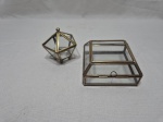 Lote de 2 caixas decorativas em vidro incolor com acabamento em metal dourado. Medindo a maior 10,5cm x 10,5cm x 5,5cm de altura. Com leve trincado em uma delas.