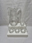 Jarra com 4 copos de suco em cristal incolor com lapidação trigo. Medindo a jarra 24cm de altura e os copos 7cm x 11cm de altura.