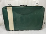 Mala de viagem vintage em material sintético na cor verde com faixa decorativa vertical bege, interior forrado com padronagem geométrica e fechos metálicos frontais. Medindo 70cm x 46cm x 17cm de altura.