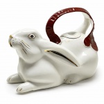 PORCELANA - Bule em formato de coelho, alça vinho e detalhes dourados. Med. 14x20x10 cm. Marcas do tempo e de uso.