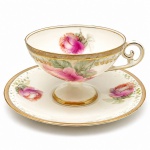 PORCELANA - Parte de grande coleção de xícaras - Bela xícara em porcelana PRUSSIA, em tom bege, flores policromadas e detalhes dourados. Med. 6x11,5 cm e 14 cm. Marcas do tempo e desgastes. Pires colados.