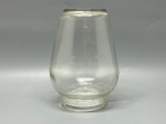 Antiga tulipa, cúpula ou globo para iluminação (provável componente de lampião ou sistema de suspensão rural), confeccionado em vidro moldado translúcido liso. Apresenta formato bulboso com base circular de encaixe estreita e boca superior levemente afunilada com terminação reta. Medidas: 14x6,5x6 cm. Apresenta marcas do tempo, de uso e bicados.