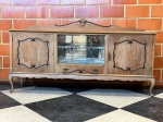 MOBILIÁRIO - Elegante aparador ou buffet em madeira nobre clara. Móvel com pés estilizados no estilo Luís XV, portas laterais em madeira com apliques decorativos em relevo, e compartimento central envidraçado com prateleiras e fundo espelhado, ostentando delicados detalhes florais gravados no vidro. Conta ainda com uma gaveta inferior central com puxadores trabalhados e testeira superior ornamentada com entalhe em concha. Med. 114x205x48 cm. <br><br>Móveis Usados - Lote de móvel antigo e usado, podendo apresentar marcas de uso e desgaste natural do tempo. Há possibilidade de danos ocultos e ou outras imperfeições. Não há garantia ou possibilidade de devolução após a aquisição. Recomenda-se inspeção prévia.