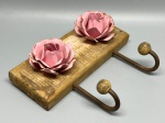 DIVERSOS - Charmoso cabideiro decorativo de parede confeccionado em base de madeira rústica de demolição, adornado com duas rosas metálicas em tons de rosa com acabamento envelhecido e equipado com dois ganchos de ferro com ponteiras esféricas. Med. 16x20 cm Marcas do tempo.
