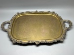 METAL - Grande bandeja em metal espessurado a prata com fundo lavrado, pés de apoio ornamentados, além de borda e alças ricamente trabalhadas em relevo com motivos de arabescos e conchas. Med. 5x72x45 cm. Desgastes, marcas do tempo e de uso.