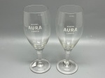 DEMI CRISTAL - Elegante par de taças de vidro para cerveja com haste e base de apoio, apresentando gravação institucional e o logotipo da marca "Bohemia Aura Lager" com marcação de capacidade de 300 ml. Alt. 20 cm.