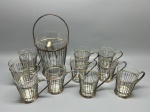 METAL - Sofisticado conjunto de bar em metal espessurado a prata e copos/balde em demi cristal, composto por um balde para gelo com alça e pinça dedicada, acompanhado por um conjunto de 8 copos com suportes vazados (porta-copos com alça). Peças elegantes com pátina original do tempo. Med. 27 cm e 11 cm. Marcas do tempo e de uso.