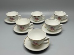 PORCELANA - Conjunto composto por seis xícaras de chá e seus respectivos pires em porcelana branca nacional da marca Porcelana Pozzani Jundiaí, apresentando bordas com acabamento em faixa dourada e delicada estampa floral de rosas cor-de-rosa com botões e folhagens tanto nas xícaras quanto nos pires. Med. 6x10x8,5 cm e 13 cm.