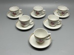 PORCELANA - Conjunto composto por seis xícaras de café e seus respectivos pires em porcelana branca nacional da marca Porcelana Pozzani Jundiaí, apresentando bordas com acabamento em faixa dourada e delicada estampa floral de rosas cor-de-rosa com botões e folhagens tanto nas xícaras quanto nos pires. Med. 5x8x6 cm e 10 cm.