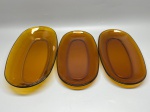 DURALEX - Lote com 3 travessas ovais em vidro âmbar, apresentando leves desgastes naturais do tempo e marcas de uso. Med. 5x34x19 cm e 3x32x18 cm.