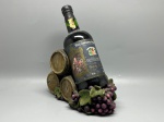 DIVERSOS - Garrafeira decorativa composta por suporte de resina ou material sintético simulando pilha de três barricas de vinho com torneiras, encimada por cachos de uvas e folhagens, acompanhada de garrafa de Vinho do Porto Dom José (Tinto Doce, 19% vol., 75 cl), engarrafado por Real Companhia Velha (Companhia Geral da Agricultura das Vinhas do Alto Douro, S.A., Vila Nova de Gaia, Portugal). Peça com desgastes do tempo e marcas de uso.