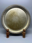METAL - Bandeja circular Wolff em metal espessurado a prata, apresentando borda com decoração em relevo de frisos e fundo ricamente ornamentado com trabalho de lavra (gravura) composto por motivos florais e padrão reticulado. Peça com marca de manufatura no verso, apresentando desgastes naturais do tempo, oxidações e marcas de uso. Dia 32 cm.