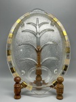 DIVERSOS - Antiga travessa oval em vidro texturizado tipo 'gelo' (sandblasted), medindo 38x27 cm, apresentando decoração na borda com quadrados intercalados em dourado e preto, contendo desenhos de flocos de neve, e estrutura central em relevo simulando a forma de uma árvore estilizada com um recipiente circular na base. Peça em bom estado de conservação, com desgastes naturais do tempo e marcas de uso.