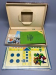 BRINQUEDO - Jogo de Ludo clássico da marca Estrela (modelo vintage original, com numeração de referência na caixa), completo com tabuleiro dobrável em papelão rígido, conjunto de peões coloridos em plástico (azul, verde, amarelo e vermelho) e o dado original. Acondicionado na caixa de papelão original ilustrada, apresentando desgaste natural pelo tempo que atesta sua autenticidade e caráter colecionável.