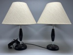 ABAJUR - Par de belos abajures de mesa (alt. 42 cm) em estilo Mid-Century Modern, estruturados com bases metálicas ponderadas, hastes cromadas e corpos centrais torneados em madeira escura, acompanhados por cúpulas cônicas originais revestidas em tecido claro de trama rústica.