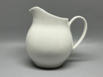 PORCELANA - Antiga jarra leiteira em porcelana branca de corpo bojondo, alça lateral delicada e bico vertedor proeminente, com altura de 16 cm.