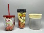 DIVERSOS - Copo natalino com glitter: Copo de acrílico transparente com tampa vermelha e canudo, contendo glitter interno nas cores vermelha e verde e estampa temática festiva com a frase "Get your Merry on" - Copo térmico decorado: Copo térmico com tampa rosca preta, revestido internamente com estampa colorida em tons de amarelo e marrom inspirada em folhagens e a inscrição "#sintaacorrida" - Pote cofrinho transparente: Recipiente cilíndrico de acrílico transparente acompanhado de tampa amarela com fenda superior para inserção de moedas e cédulas.